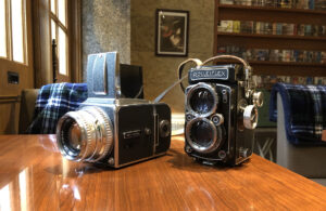 木製テーブルの上に並べられたHasselbladとRolleiflexの中判フィルムカメラ