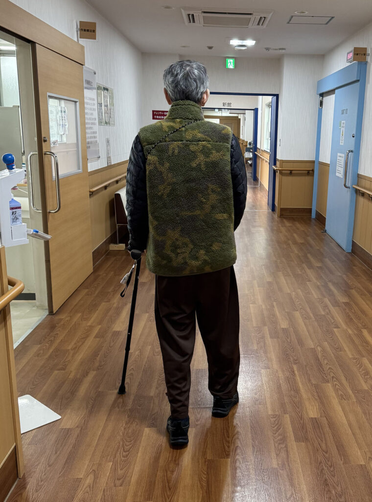 段差のない病院内の廊下を杖で歩く回復期リハビリの様子